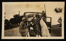 Three unidentified women posing at the back of a car