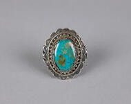 Silver ring with bezel-set cabochon turquoise flanked by tulip-shaped decorative elements on the band.